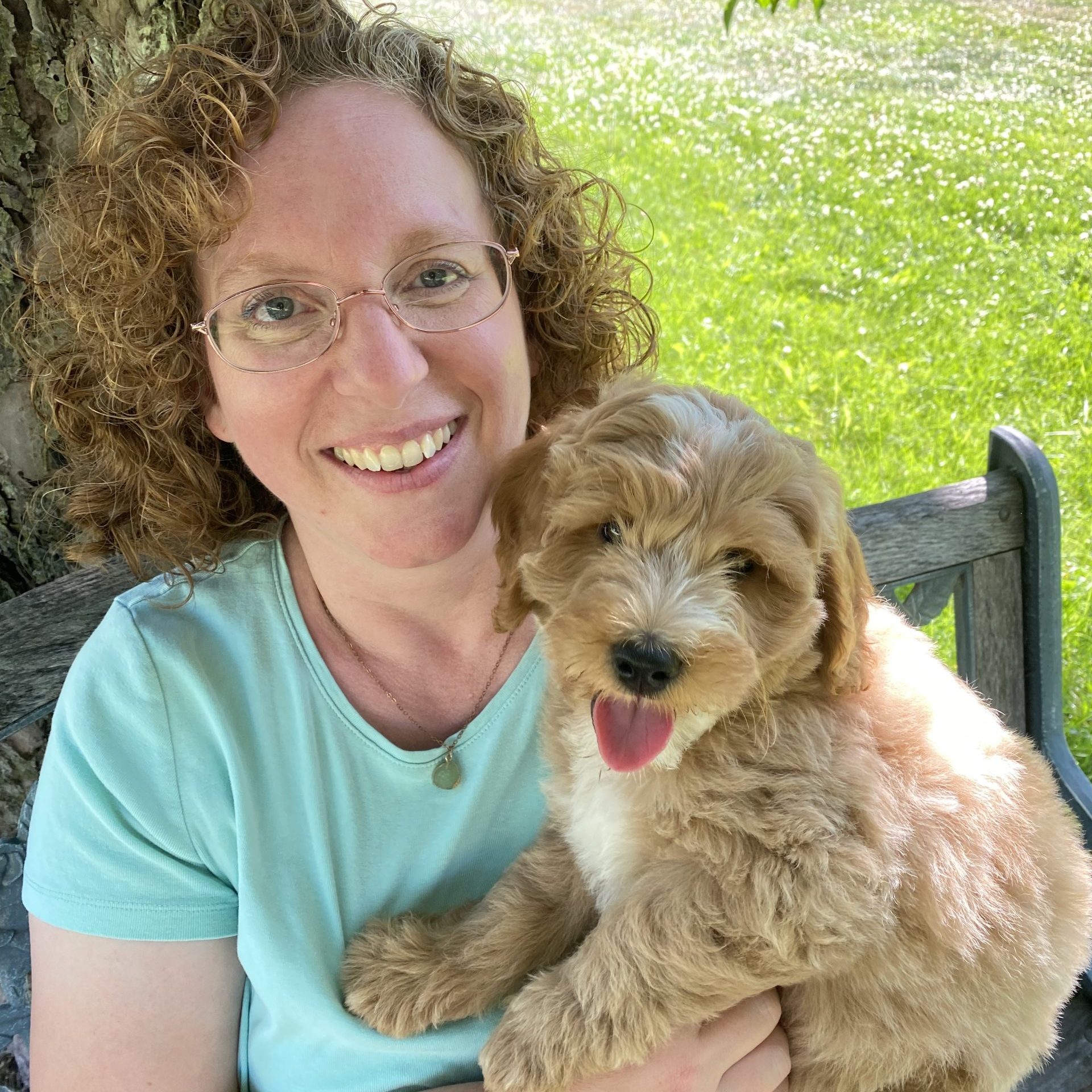 Amy and puppy on bench under tree