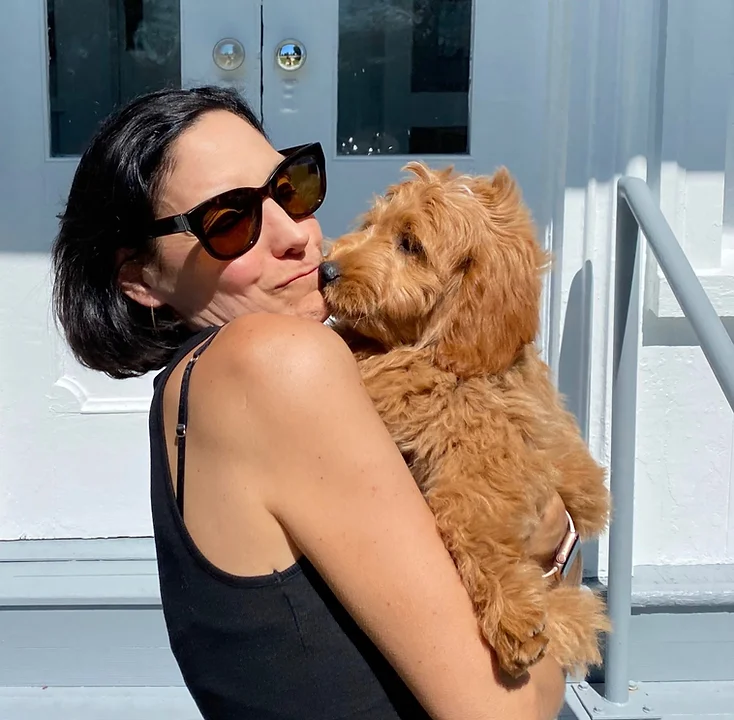 Happy customer holding puppy from NY Dandy Doodles in front of doors